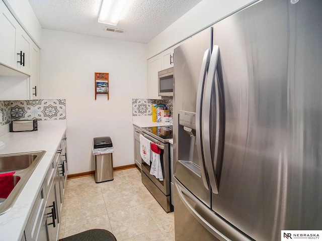 2425 Folkways Blvd Unit 211, Lincoln, NE 68521 - kitchen featuring appliances with stainless steel finishes, backsplash, white cabinetry, and a textured ceiling