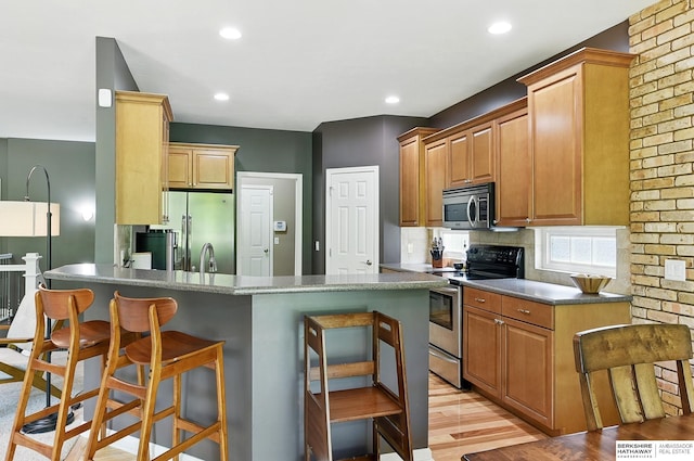 408 S 197th St, Omaha, NE 68022 - kitchen featuring stainless steel appliances, a kitchen bar, a peninsula, light wood-style floors, and decorative backsplash