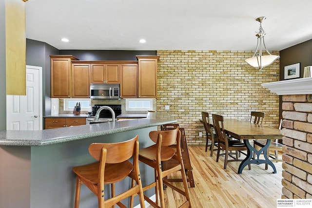 408 S 197th St, Omaha, NE 68022 - kitchen featuring stainless steel microwave, a kitchen bar, backsplash, stove, and light wood-style flooring