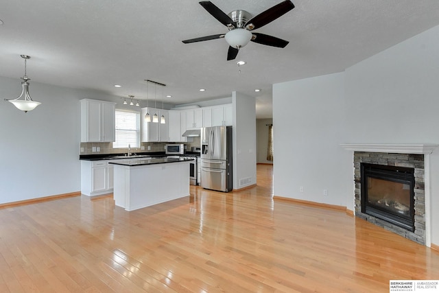 16332 Patrick Ave, Omaha, NE 68116 - kitchen featuring stainless steel appliances, open floor plan, a ceiling fan, dark countertops, and under cabinet range hood