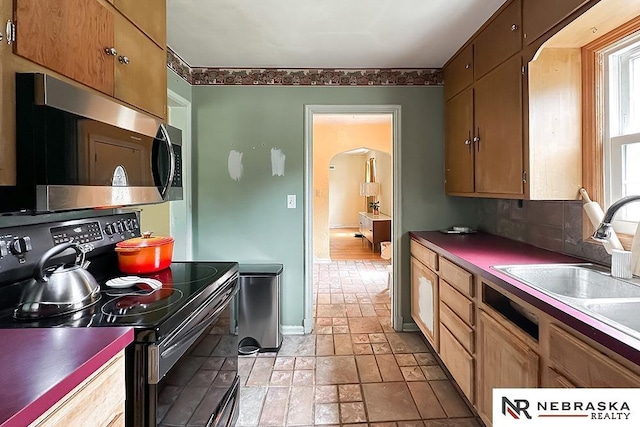 3340 N 48th Ave, Omaha, NE 68104 - kitchen with electric range oven, stainless steel microwave, light stone finish floors, and arched walkways