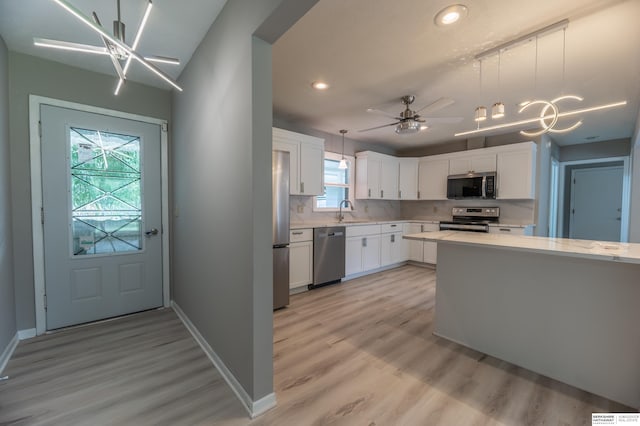 3701 Groves Rd, Bellevue, NE 68147 - kitchen with appliances with stainless steel finishes, light wood-style flooring, recessed lighting, white cabinetry, and tasteful backsplash