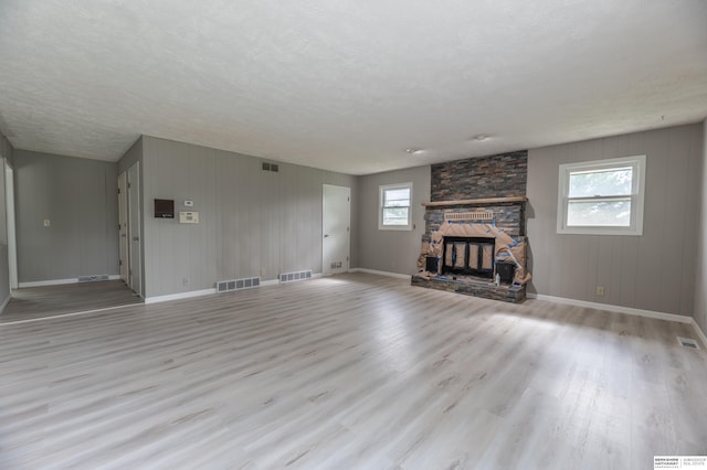 3701 Groves Rd, Bellevue, NE 68147 - unfurnished living room featuring light wood-style floors, a textured ceiling, and a stone fireplace