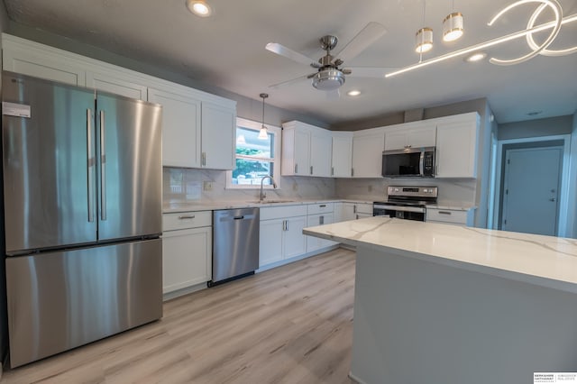 3701 Groves Rd, Bellevue, NE 68147 - kitchen with stainless steel appliances, light wood finished floors, backsplash, white cabinets, and a ceiling fan