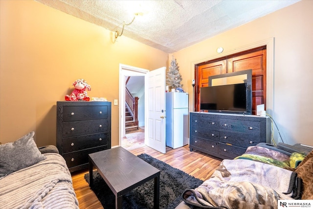 2567 Marcy St, Omaha, NE 68105 - living room with light wood-type flooring, a textured ceiling, and stairs