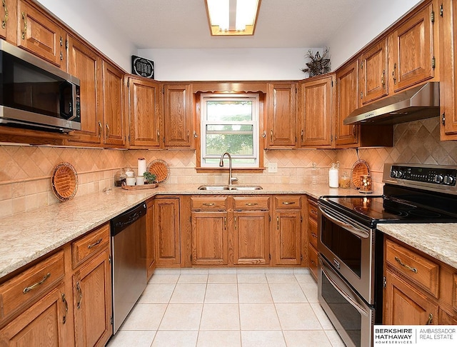 5511 S 104th Cir, Omaha, NE 68127 - kitchen with appliances with stainless steel finishes, under cabinet range hood, brown cabinetry, and tasteful backsplash