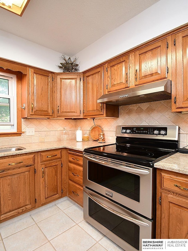 5511 S 104th Cir, Omaha, NE 68127 - kitchen with stainless steel range with electric stovetop, under cabinet range hood, brown cabinets, and decorative backsplash