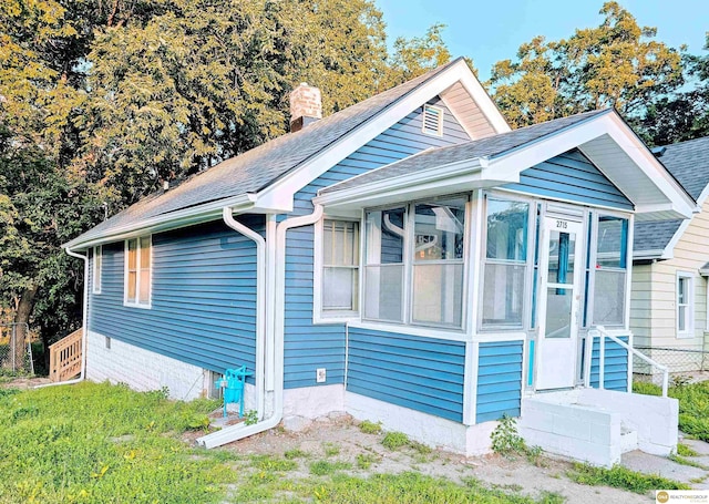 2715 S 15th St, Omaha, NE 68108 - view of home's exterior featuring a chimney, a shingled roof, and a sunroom