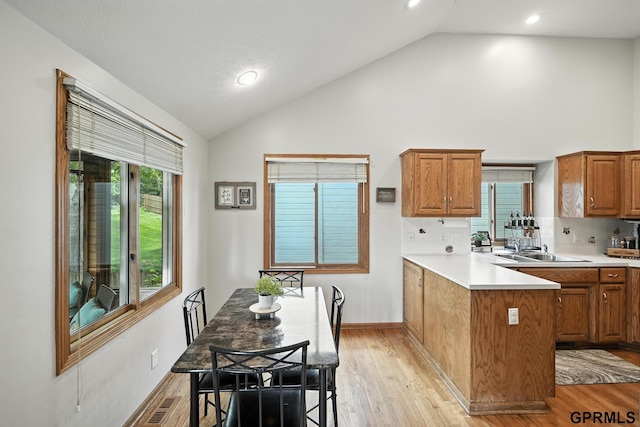 2303 N 150th Ave, Omaha, NE 68116 - kitchen with a peninsula, light countertops, brown cabinets, light wood-type flooring, and high vaulted ceiling