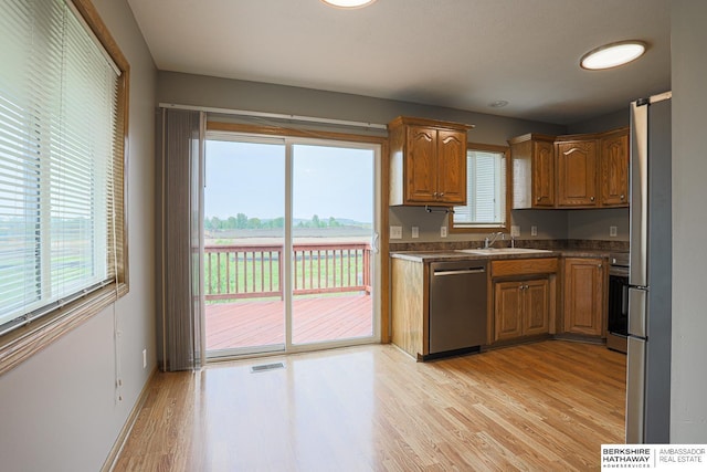 32 Huron Cir, Council Bluffs, IA 51501 - kitchen with appliances with stainless steel finishes, light wood finished floors, brown cabinetry, and dark countertops