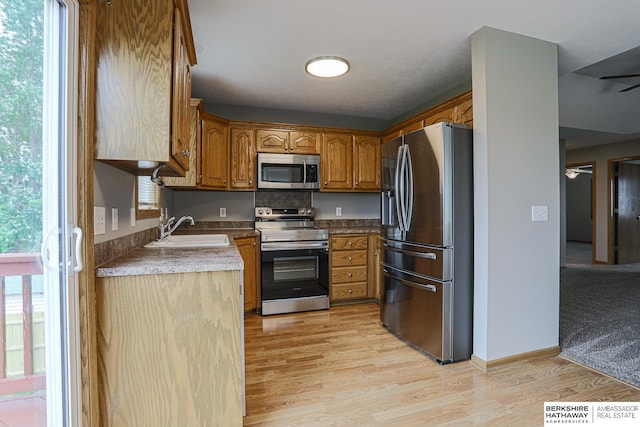 32 Huron Cir, Council Bluffs, IA 51501 - kitchen with appliances with stainless steel finishes, brown cabinetry, light wood-style floors, and ceiling fan