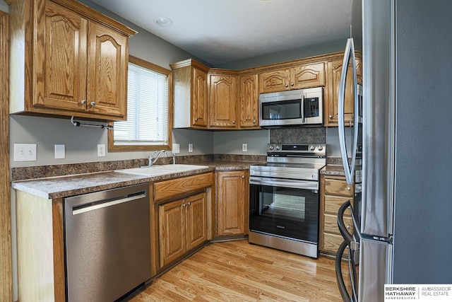 32 Huron Cir, Council Bluffs, IA 51501 - kitchen with appliances with stainless steel finishes, dark countertops, light wood-style flooring, and brown cabinets