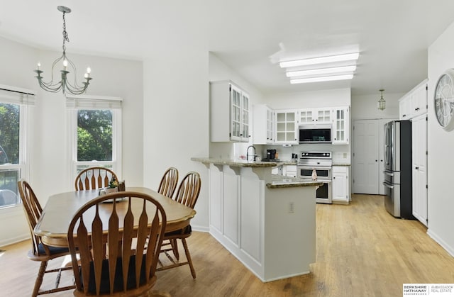 1326 Bellevue Blvd, Bellevue, NE 68005 - kitchen with appliances with stainless steel finishes, a peninsula, light stone countertops, light wood-type flooring, and a chandelier