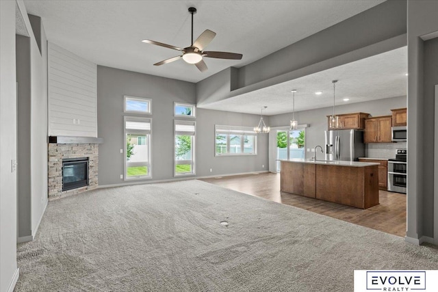 12040 S 44th St, Bellevue, NE 68123 - unfurnished living room featuring carpet flooring, ceiling fan, a stone fireplace, recessed lighting, and a chandelier