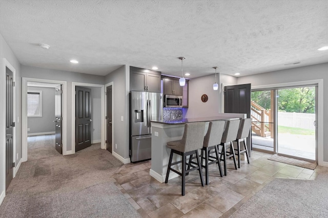 2111 Gindy Dr, Bellevue, NE 68147 - kitchen featuring stainless steel appliances, a breakfast bar, a textured ceiling, a center island, and pendant lighting
