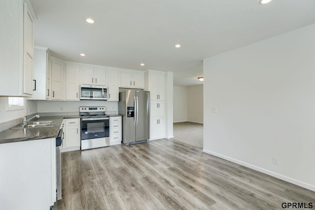 2507 Murray Rd, Plattsmouth, NE 68048 - kitchen with appliances with stainless steel finishes, dark countertops, recessed lighting, light wood-style flooring, and white cabinetry