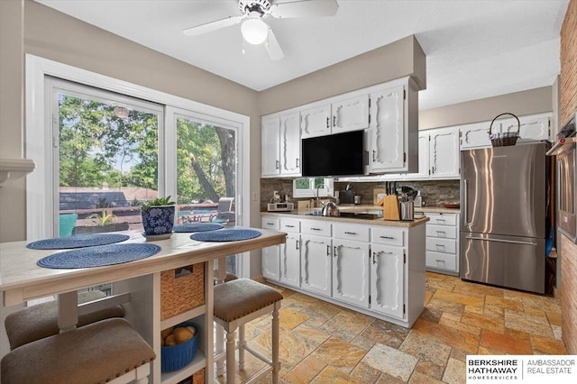 247 N 117th Ave, Omaha, NE 68154 - kitchen featuring freestanding refrigerator, backsplash, white cabinetry, and stone tile flooring