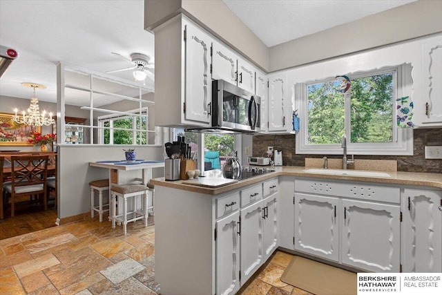247 N 117th Ave, Omaha, NE 68154 - kitchen with stainless steel microwave, a ceiling fan, stone tile floors, and decorative backsplash
