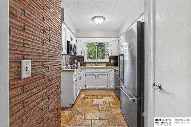 247 N 117th Ave, Omaha, NE 68154 - kitchen featuring appliances with stainless steel finishes, stone tile floors, white cabinetry, light countertops, and backsplash
