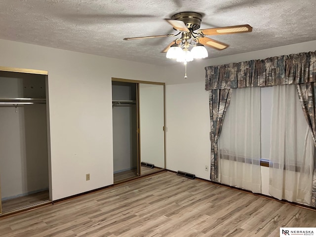 6211 S 150th St, Omaha, NE 68137 - unfurnished bedroom with multiple closets, wood finished floors, a textured ceiling, and ceiling fan