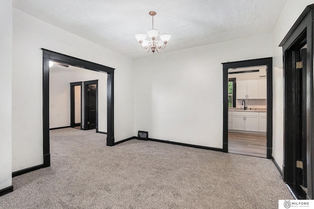 4419 N 39th St, Omaha, NE 68111 - empty room featuring light colored carpet, a chandelier, and a textured ceiling