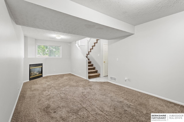 17737 Edna St, Omaha, NE 68136 - below grade area with a textured ceiling, stairway, a glass covered fireplace, and carpet floors