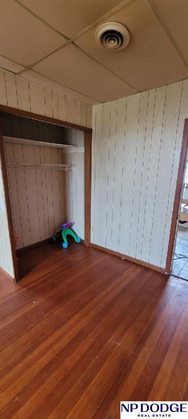 609 Howard St, Scribner, NE 68057 - unfurnished bedroom featuring hardwood / wood-style flooring and wooden walls