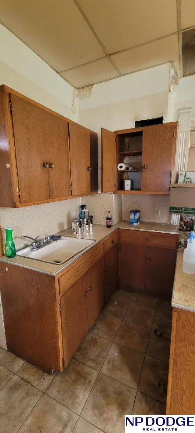 609 Howard St, Scribner, NE 68057 - kitchen featuring open shelves, light countertops, light tile patterned flooring, and brown cabinetry