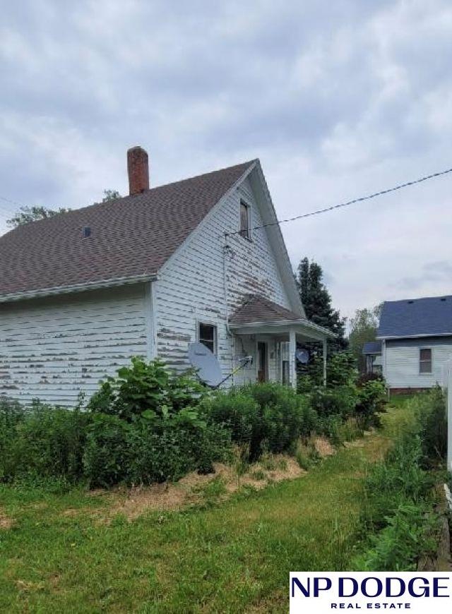 609 Howard St, Scribner, NE 68057 - view of home's exterior featuring a chimney and roof with shingles