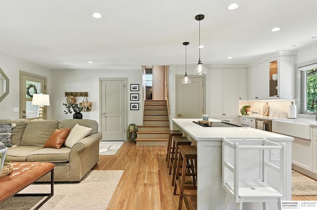 9903 Pasadena Ave, Omaha, NE 68124 - kitchen featuring light countertops, white cabinetry, open floor plan, a breakfast bar area, and recessed lighting