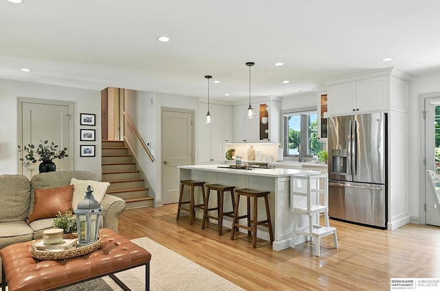 9903 Pasadena Ave, Omaha, NE 68124 - kitchen featuring stainless steel fridge with ice dispenser, light wood-type flooring, a center island, light countertops, and a breakfast bar area
