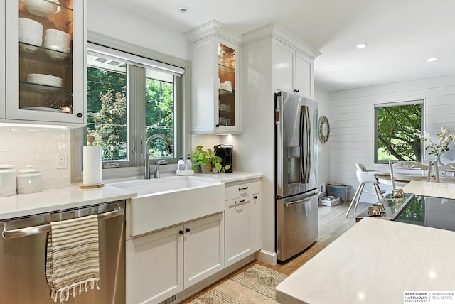 9903 Pasadena Ave, Omaha, NE 68124 - kitchen featuring stainless steel appliances, light countertops, light wood finished floors, white cabinetry, and backsplash