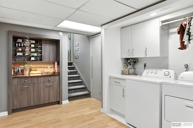 9903 Pasadena Ave, Omaha, NE 68124 - washroom with washing machine and clothes dryer, cabinet space, light wood-type flooring, and bar