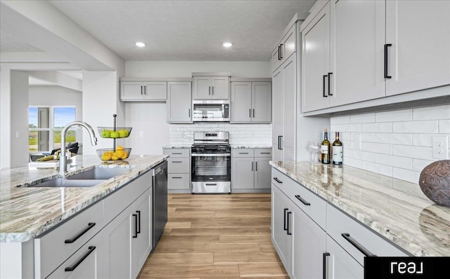 7409 N 176th Ave, Bennington, NE 68007 - kitchen featuring stainless steel appliances, decorative backsplash, light wood finished floors, recessed lighting, and light stone counters
