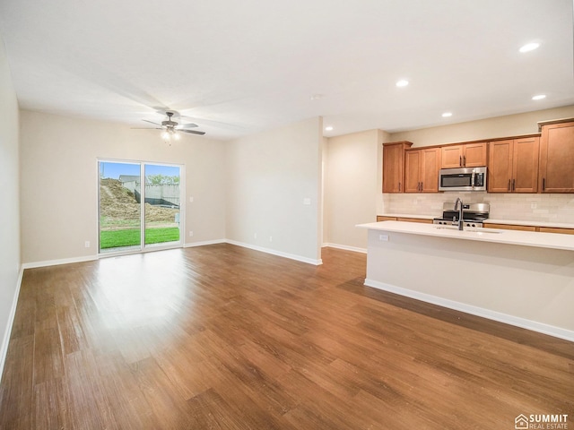 1120 Titan Dr, Hickman, NE 68372 - kitchen featuring stainless steel microwave, light countertops, decorative backsplash, wood finished floors, and a ceiling fan