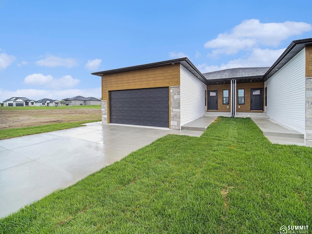 1130 Titan Dr, Hickman, NE 68372 - contemporary house featuring an attached garage, a front yard, concrete driveway, and stone siding