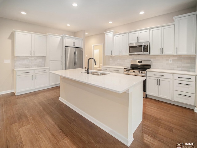 1130 Titan Dr, Hickman, NE 68372 - kitchen with appliances with stainless steel finishes, wood finished floors, tasteful backsplash, an island with sink, and recessed lighting