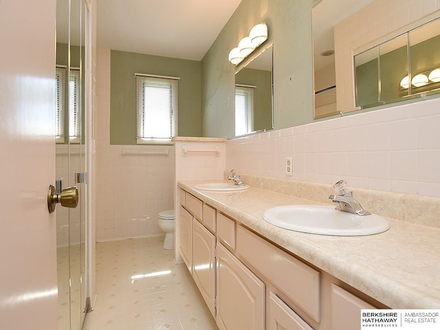 1502 Sunshine Blvd, Bellevue, NE 68123 - bathroom featuring tile walls, double vanity, wainscoting, and tile patterned floors