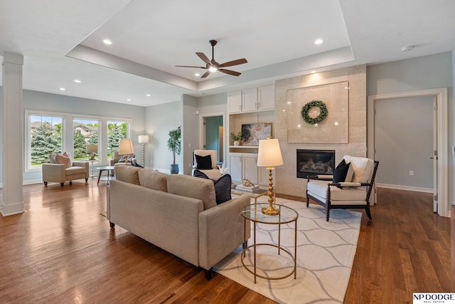 1320 S 190th Plz, Omaha, NE 68130 - living area with a tray ceiling, wood finished floors, a ceiling fan, a tiled fireplace, and recessed lighting