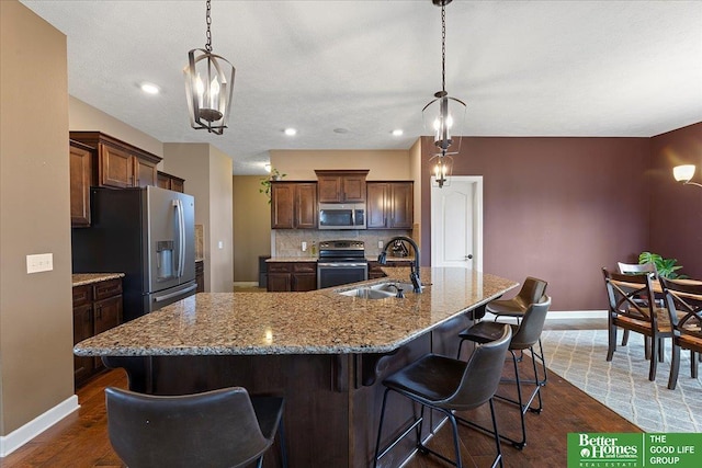 14611 S 24th St, Bellevue, NE 68123 - kitchen with appliances with stainless steel finishes, dark wood finished floors, decorative backsplash, a kitchen breakfast bar, and a large island with sink