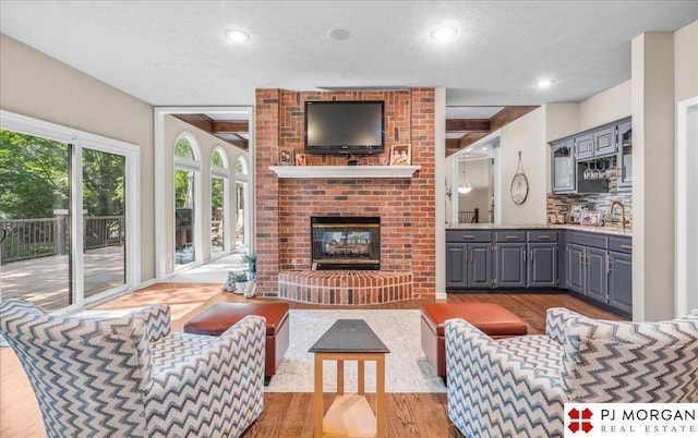 733 N 157th Cir, Omaha, NE 68118 - living area featuring wood finished floors, a textured ceiling, a brick fireplace, and recessed lighting