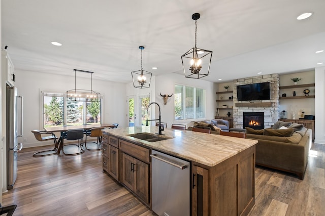 21034 X St, Omaha, NE 68022 - kitchen with stainless steel appliances, a stone fireplace, dark wood-style floors, recessed lighting, and a kitchen island with sink