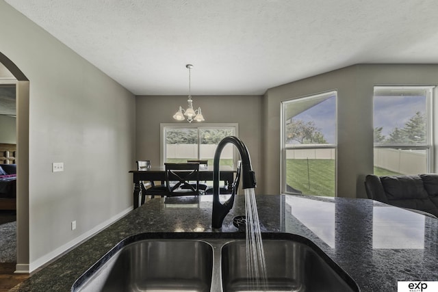 6015 S 193rd St, Omaha, NE 68135 - kitchen view of a chandelier, arched walkways, dark stone countertops, and decorative light fixtures