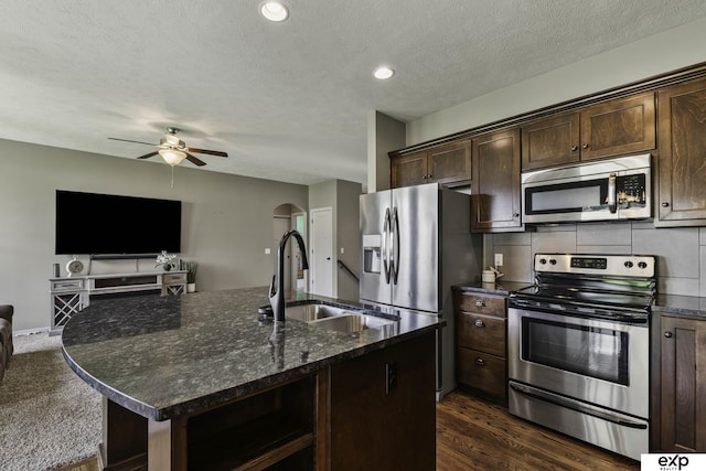 6015 S 193rd St, Omaha, NE 68135 - kitchen featuring stainless steel appliances, open floor plan, dark brown cabinetry, a ceiling fan, and a kitchen island with sink