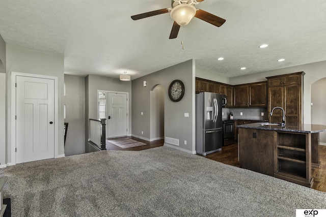 6015 S 193rd St, Omaha, NE 68135 - kitchen with stainless steel refrigerator with ice dispenser, arched walkways, dark brown cabinetry, dark stone counters, and ceiling fan