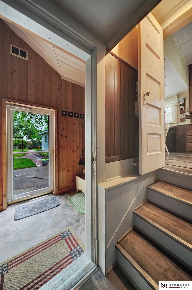 6409 Logan Ave, Lincoln, NE 68507 - staircase featuring vaulted ceiling, wood walls, and stone finish flooring