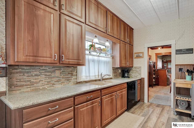 6409 Logan Ave, Lincoln, NE 68507 - kitchen featuring wallpapered walls, black dishwasher, light wood-type flooring, brown cabinetry, and decorative backsplash