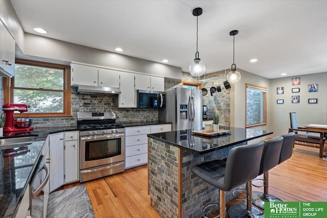 754 10th St, Syracuse, NE 68446 - kitchen featuring appliances with stainless steel finishes, under cabinet range hood, healthy amount of natural light, light wood-type flooring, and recessed lighting