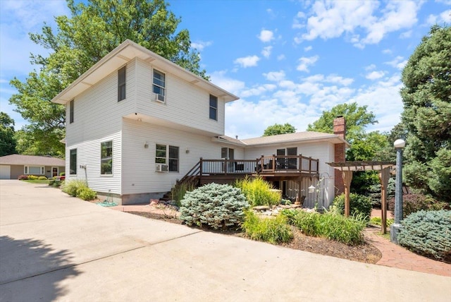 754 10th St, Syracuse, NE 68446 - back of property with a wooden deck, a chimney, stairs, cooling unit, and a garage