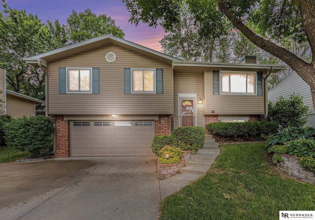 2219 Independence Dr, Lincoln, NE 68521 - raised ranch with a garage, driveway, brick siding, and a chimney